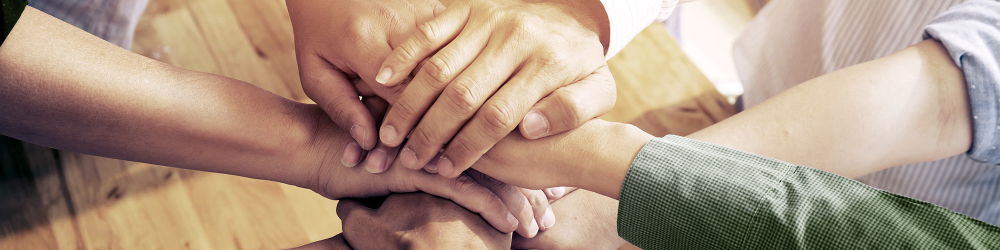 People Putting Their Hands Together In Cooperation